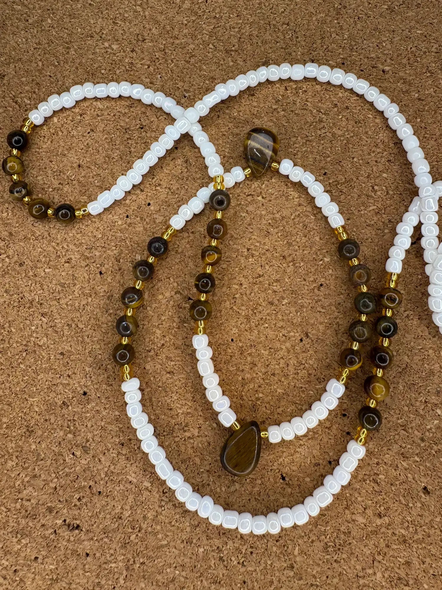 Un délicat collier composé de perles de pierres fines alternant des perles blanches et celles de l’œil-de-tigre, rehaussé d’intercalaires dorés aux dimensions délicates.